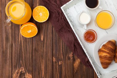 Fırından yeni çıkmış kruvasan, portakal suyu, taze meyve, kahverengi ahşap arka plan üzerinde reçel. Fransız kahvaltı. Taze hamur işleri sabah için. Lezzetli tatlı. Üstten Görünüm. Portre fotoğrafçılığı. Yatay başlık