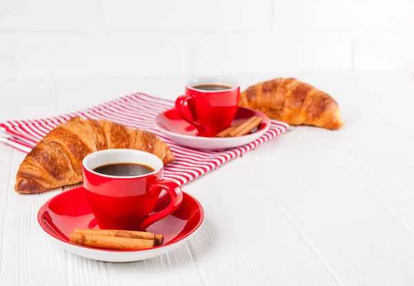 Frisch gebackenes Croissant auf Serviette, Tasse Kaffee in roter Tasse auf weißem Holzgrund. Französisches Frühstück. frisches Gebäck zum Frühstück. leckeres Dessert. Nahaufnahmen. horizontales Banner — Stockfoto
