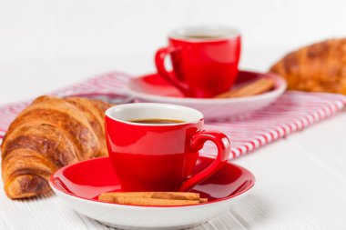 Taze pişmiş kruvasan peçete, Beyaz ahşap zemin üzerinde kırmızı Kupası kahve üzerinde. Fransız kahvaltı. Kahvaltı için taze hamur işleri. Lezzetli tatlı. Portre fotoğrafçılığı. Yatay başlık