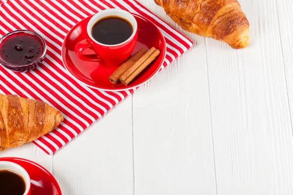 Taze pişmiş kruvasan peçete, Beyaz ahşap zemin üzerinde kırmızı Kupası kahve üzerinde. Fransız kahvaltı. Kahvaltı için taze hamur işleri. Lezzetli tatlı. Portre fotoğrafçılığı. Yatay başlık