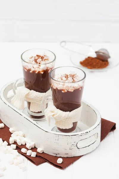 Warm cocoa in glasses with marshmallow, crocahet decorations, brown and beige napkins on white wooden background. Hot chocolate. Sweet drink. Close up photography. Vertical banner — Stock Photo, Image