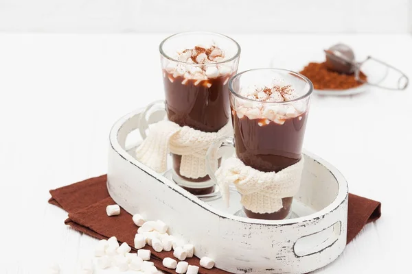 Warm cocoa in glasses with marshmallow, crocahet decorations, brown and beige napkins on white wooden background. Hot chocolate. Sweet drink. Close up photography. Hoizontal banner — Stock Photo, Image