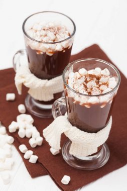 Hatmi, crocahet süslemeleri, Beyaz ahşap zemin üzerinde kahverengi ve bej peçete ile bardaklarda sıcak kakao. Sıcak çikolata. Tatlı içki. Fotoğraf kadar kapatın. Dikey başlık