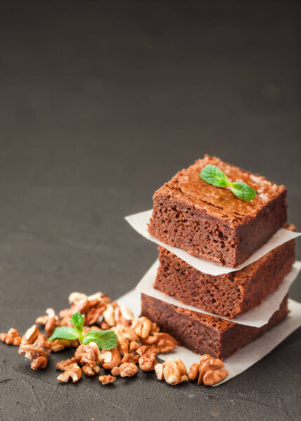 Выбирайте квадратные кусочки в стопку на белой тарелке с грецкими орехами, украшенные листьями мяты и кокосом на черном фоне. Вкусный десерт. Темное настроение. Закройте фотографию. Селективный фокус
.