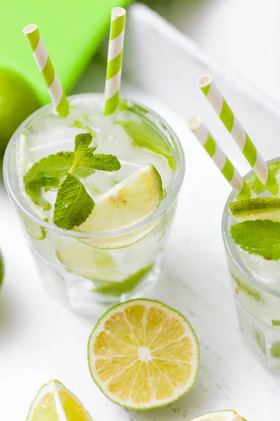 Caipirinha, mojito cocktail με lime, καστανή ζάχαρη, πάγο και δυόσμο φύλλα σε όμορφα γυαλιά, κομμένα πράσινο εσπεριδοειδή σε άσπρο φόντο ξύλινη. Αλκοόλη ποτό το καλοκαίρι. Κλείστε τη φωτογραφία. Επιλεκτική εστίαση — Φωτογραφία Αρχείου