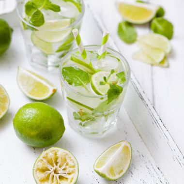 Caipirinha, mojito kireç, kahverengi şeker, buz ve nane ile kokteyl yaprakları yeşil narenciye Beyaz ahşap arka plan üzerinde kesme güzel gözlük. Yaz alkol içki. Fotoğraf kadar kapatın. Seçici odak