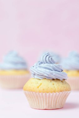Cupcake pastel pembe bir arka plan üzerinde Menekşe buttercream ile dekore edilmiştir. Tatlı güzel pasta. Dikey afiş, düğün, doğum günü, kadınlar günü için tebrik kartı. Fotoğraf kadar kapatın. Seçici odak
