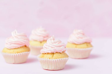 Cupcake pastel pembe bir arka plan üzerinde pembe buttercream ile dekore edilmiştir. Tatlı güzel pasta. Yatay banner, düğün, doğum günü, kadınlar günü için tebrik kartı. Fotoğraf kadar kapatın. Seçici odak