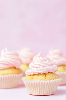 Cupcake pastel pembe bir arka plan üzerinde pembe buttercream ile dekore edilmiştir. Tatlı güzel pasta. Dikey afiş, düğün, doğum günü, kadınlar günü için tebrik kartı. Fotoğraf kadar kapatın. Seçici odak