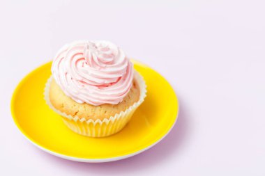Cupcake pembe buttercream pastel pembe bir arka plan üzerinde parlak sarı plaka ile dekore edilmiştir. Tatlı güzel pasta. Yatay banner, tebrik kartı, tebrik. Fotoğraf kadar kapatın. Seçici odak