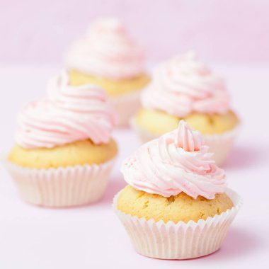 Cupcake pastel pembe bir arka plan üzerinde pembe buttercream ile dekore edilmiştir. Tatlı güzel pasta. Afiş, düğün, doğum günü, kadınlar günü için tebrik kartı kare. Fotoğraf kadar kapatın. Seçici odak