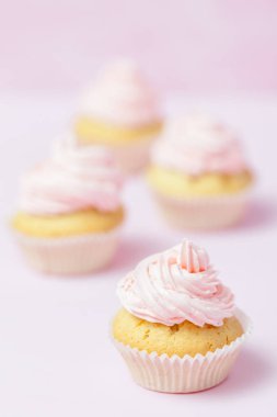 Cupcake pastel pembe bir arka plan üzerinde pembe buttercream ile dekore edilmiştir. Tatlı güzel pasta. Dikey afiş, düğün, doğum günü, kadınlar günü için tebrik kartı. Fotoğraf kadar kapatın. Seçici odak
