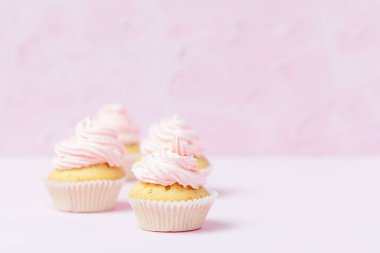Cupcake pastel pembe bir arka plan üzerinde pembe buttercream ile dekore edilmiştir. Tatlı güzel pasta. Yatay banner, düğün, doğum günü, kadınlar günü için tebrik kartı. Fotoğraf kadar kapatın. Seçici odak