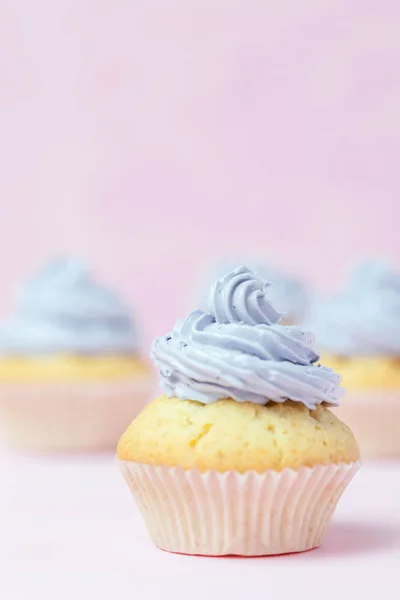 Cupcake dekorerad med violett smörkräm på pastell rosa bakgrund. Söta vacker tårta. Vertikal banner, gratulationskort för födelsedag, bröllop, kvinnodagen. Närbild av fotografi. Selektivt fokus — Stockfoto