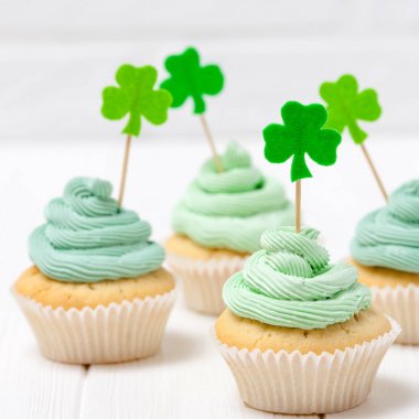 Aziz Patrick günü Tema renkli yatay banner. Cupcakes yeşil buttercream ile dekore edilmiş ve craft dekorasyon shamrock şeklinde yaprakları beyaz arka plan üzerinde hissettim. Uzay kopyalayın. Tebrik kartı