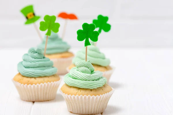 Thème de la Saint-Patrick bannière horizontale colorée. Gâteaux décorés avec de la crème au beurre verte et des décorations artisanales en feutre sous forme de chapeau de lutin, moustache, feuilles de trèfle sur fond blanc — Photo