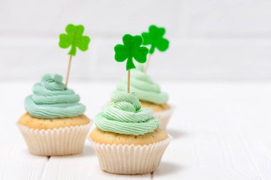 Aziz Patrick günü Tema renkli yatay banner. Cupcakes yeşil buttercream ile dekore edilmiş ve craft dekorasyon shamrock şeklinde yaprakları beyaz arka plan üzerinde hissettim. Uzay kopyalayın. Tebrik kartı