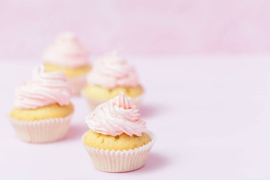 Cupcake pastel pembe bir arka plan üzerinde pembe buttercream ile dekore edilmiştir. Tatlı güzel pasta. Yatay banner, düğün, doğum günü, kadınlar günü için tebrik kartı. Fotoğraf kadar kapatın. Seçici odak