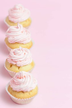 Cupcake pastel pembe bir arka plan üzerinde pembe buttercream ile dekore edilmiştir. Tatlı güzel pasta. Dikey afiş, düğün, doğum günü, kadınlar günü için tebrik kartı. Fotoğraf kadar kapatın. Seçici odak