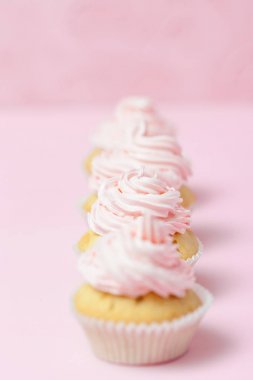 Cupcake pastel pembe bir arka plan üzerinde pembe buttercream ile dekore edilmiştir. Tatlı güzel pasta. Dikey afiş, düğün, doğum günü, kadınlar günü için tebrik kartı. Fotoğraf kadar kapatın. Seçici odak
