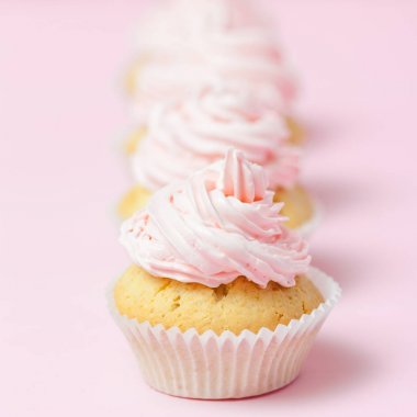 Cupcake pastel pembe bir arka plan üzerinde pembe buttercream ile dekore edilmiştir. Tatlı güzel pasta. Afiş, düğün, doğum günü, kadınlar günü için tebrik kartı kare. Fotoğraf kadar kapatın. Seçici odak
