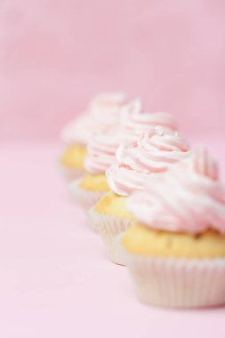 Cupcake pastel pembe bir arka plan üzerinde pembe buttercream ile dekore edilmiştir. Tatlı güzel pasta. Dikey afiş, düğün, doğum günü, kadınlar günü için tebrik kartı. Fotoğraf kadar kapatın. Seçici odak