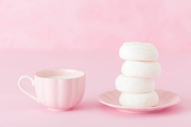 Zephyr'i dessrt pembe plaka, pastel pembe arka plan üzerine sütlü kahve fincan beyaz. Güzel tatlılar. Yatay banner, tebrik kartı için doğum günü, düğün. Fotoğraf kadar kapatın. Seçici odak