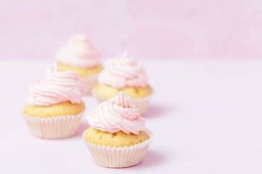 Cupcake pastel pembe bir arka plan üzerinde pembe buttercream ile dekore edilmiştir. Tatlı güzel pasta. Yatay banner, düğün, doğum günü, kadınlar günü için tebrik kartı. Fotoğraf kadar kapatın. Seçici odak