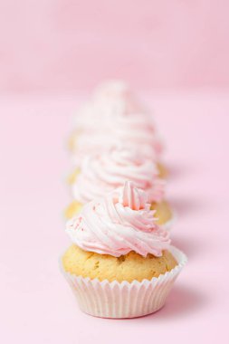 Cupcake pastel pembe bir arka plan üzerinde pembe buttercream ile dekore edilmiştir. Tatlı güzel pasta. Dikey afiş, düğün, doğum günü, kadınlar günü için tebrik kartı. Fotoğraf kadar kapatın. Seçici odak