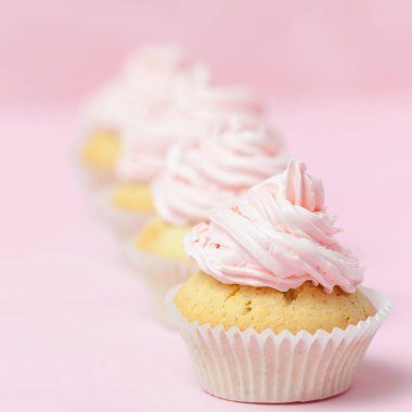 Cupcake pastel pembe bir arka plan üzerinde pembe buttercream ile dekore edilmiştir. Tatlı güzel pasta. Afiş, düğün, doğum günü, kadınlar günü için tebrik kartı kare. Fotoğraf kadar kapatın. Seçici odak