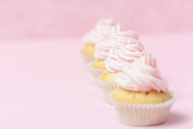 Cupcake pastel pembe bir arka plan üzerinde pembe buttercream ile dekore edilmiştir. Tatlı güzel pasta. Yatay banner, düğün, doğum günü, kadınlar günü için tebrik kartı. Fotoğraf kadar kapatın. Seçici odak