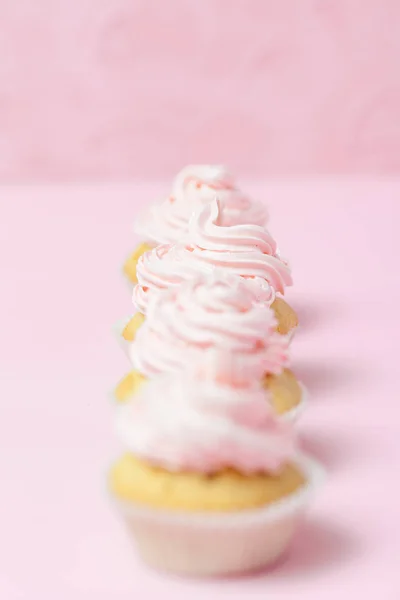 Cupcake decorated with pink buttercream on pastel pink background. Sweet beautiful cake. Vertical banner, greeting card for birthday, wedding, women\'s day. Close up photography. Selective focus