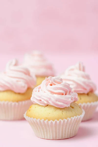 Cupcake, διακοσμημένα με ροζ buttercream σε παστέλ ροζ φόντο. Όμορφη γλυκιά τούρτα. Κατακόρυφοs σημαία, ευχετήρια κάρτα για τα γενέθλιά, γάμο, ημέρα της γυναίκας. Κλείστε τη φωτογραφία. Επιλεκτική εστίαση — Φωτογραφία Αρχείου