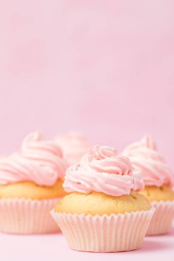 Cupcake pastel pembe bir arka plan üzerinde pembe buttercream ile dekore edilmiştir. Tatlı güzel pasta. Dikey afiş, düğün, doğum günü, kadınlar günü için tebrik kartı. Fotoğraf kadar kapatın. Seçici odak
