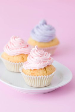 Cupcake pastel pembe arka plan üzerine pembe ve mor buttercream ile dekore edilmiştir. Tatlı güzel pasta. Dikey afiş, tebrik kartı için doğum günü, düğün. Fotoğraf kadar kapatın. Seçici odak