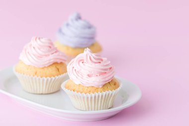 Cupcake pastel pembe arka plan üzerine pembe ve mor buttercream ile dekore edilmiştir. Tatlı güzel pasta. Yatay banner, tebrik kartı için doğum günü, düğün. Fotoğraf kadar kapatın. Seçici odak