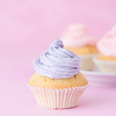 Cupcake pastel pembe arka plan üzerine pembe ve mor buttercream ile dekore edilmiştir. Tatlı güzel pasta. Kare afiş, tebrik kartı için doğum günü, düğün. Fotoğraf kadar kapatın. Seçici odak