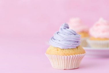 Cupcake pastel pembe arka plan üzerine pembe ve mor buttercream ile dekore edilmiştir. Tatlı güzel pasta. Yatay banner, tebrik kartı için doğum günü, düğün. Fotoğraf kadar kapatın. Seçici odak
