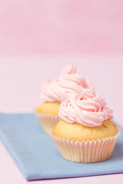 Cupcake decorated with pink buttercream on pastel pink background. Sweet beautiful cake. Vertical banner, greeting card for birthday, wedding, women\'s day. Close up photography. Selective focus