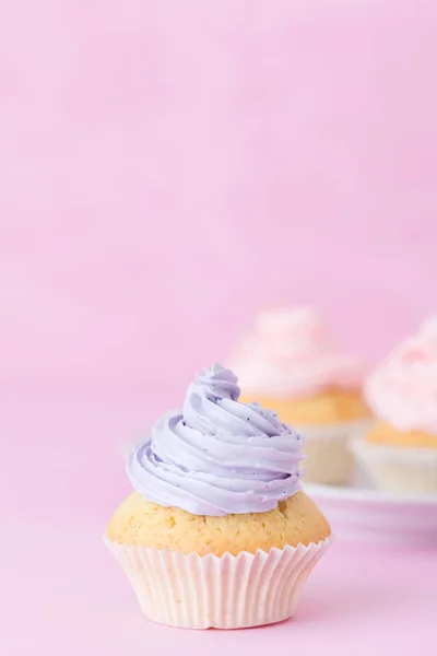 Cupcake decorado con crema de mantequilla rosa y violeta sobre fondo rosa pastel. Dulce pastel hermoso. Banner vertical, tarjeta de felicitación para cumpleaños, boda. Cierre la fotografía. Enfoque selectivo — Foto de Stock