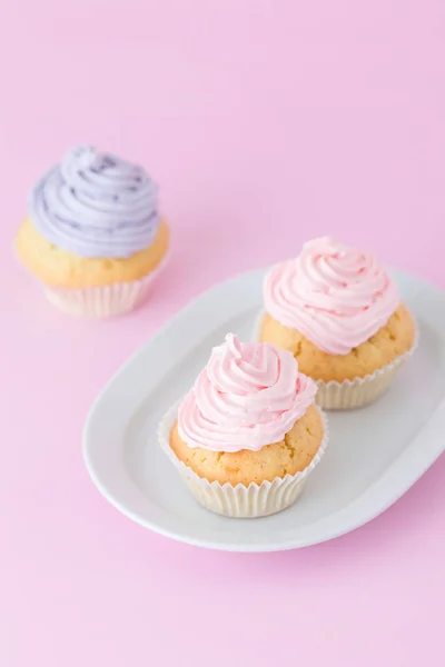 Cupcake decorado com creme de manteiga rosa e violeta em fundo rosa pastel. Doce bolo lindo. Banner vertical, cartão de felicitações para aniversário, casamento. Fotografia de perto. Foco seletivo — Fotografia de Stock