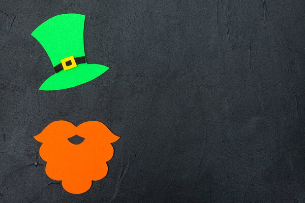 St. Patrick's Day theme colorful horizontal banner. Green leprechaun hat, beard and shamrock leaves on black background. Felt craft elements. Copy space. For greeting card, congratulation banner