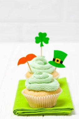 Aziz Patrick günü Tema renkli dikey banner. Cupcakes yeşil buttercream ile dekore edilmiş ve craft dekorasyon shamrock şeklinde yaprakları beyaz arka plan üzerinde hissettim. Uzay kopyalayın. Tebrik kartı
