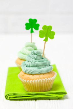 Aziz Patrick günü Tema renkli dikey banner. Cupcakes yeşil buttercream ile dekore edilmiş ve craft dekorasyon shamrock şeklinde yaprakları beyaz arka plan üzerinde hissettim. Uzay kopyalayın. Tebrik kartı