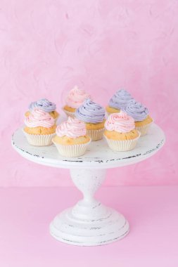 Violet ile cupcakes ve pembe krem beyaz eski püskü shic üzerinde pastel pembe arka plan