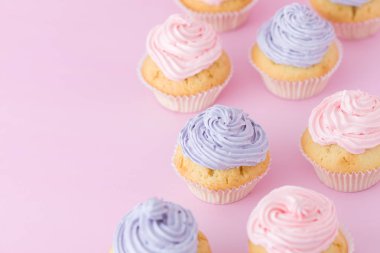 Mor ve pembe pastel pembe bir arka plan üstüne krem ayakta ile cupcakes görüntülemek.