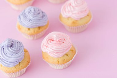 Mor ve pembe pastel pembe bir arka plan üzerinde buttercream duran ile cupcakes.