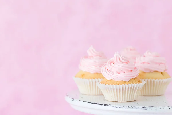 파스텔 핑크 배경에 초라한 shic 스탠드에 분홍색 buttercream 컵 케 익 장식. — 스톡 사진