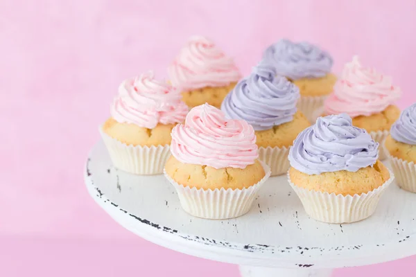 Cupcakes decorated with pink and violet buttercream on shabby shic stand on pastel pink background. — Stock Photo, Image
