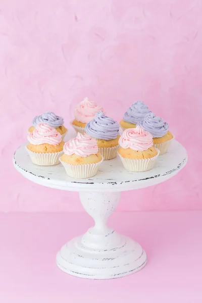 Cupcakes com creme violeta e rosa em branco shabby shic stand no fundo rosa pastel — Fotografia de Stock